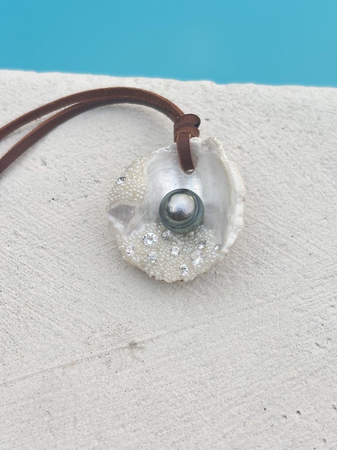 Collier en coquillage nacré avec une perle de Tahiti cerclée, photographié au bord de la piscine